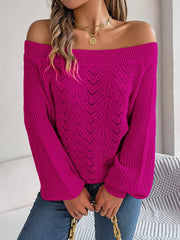 Cerise open-knit off-shoulder sweater with voluminous sleeves and chevron pattern.