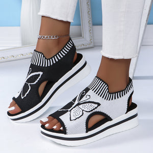 Chic open-toe wedge sandals in black and white with butterfly motif mesh detail and chunky heel.