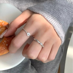 Sterling silver rings, one with a twisted band and zircon flower, the other with a textured band and small stone.