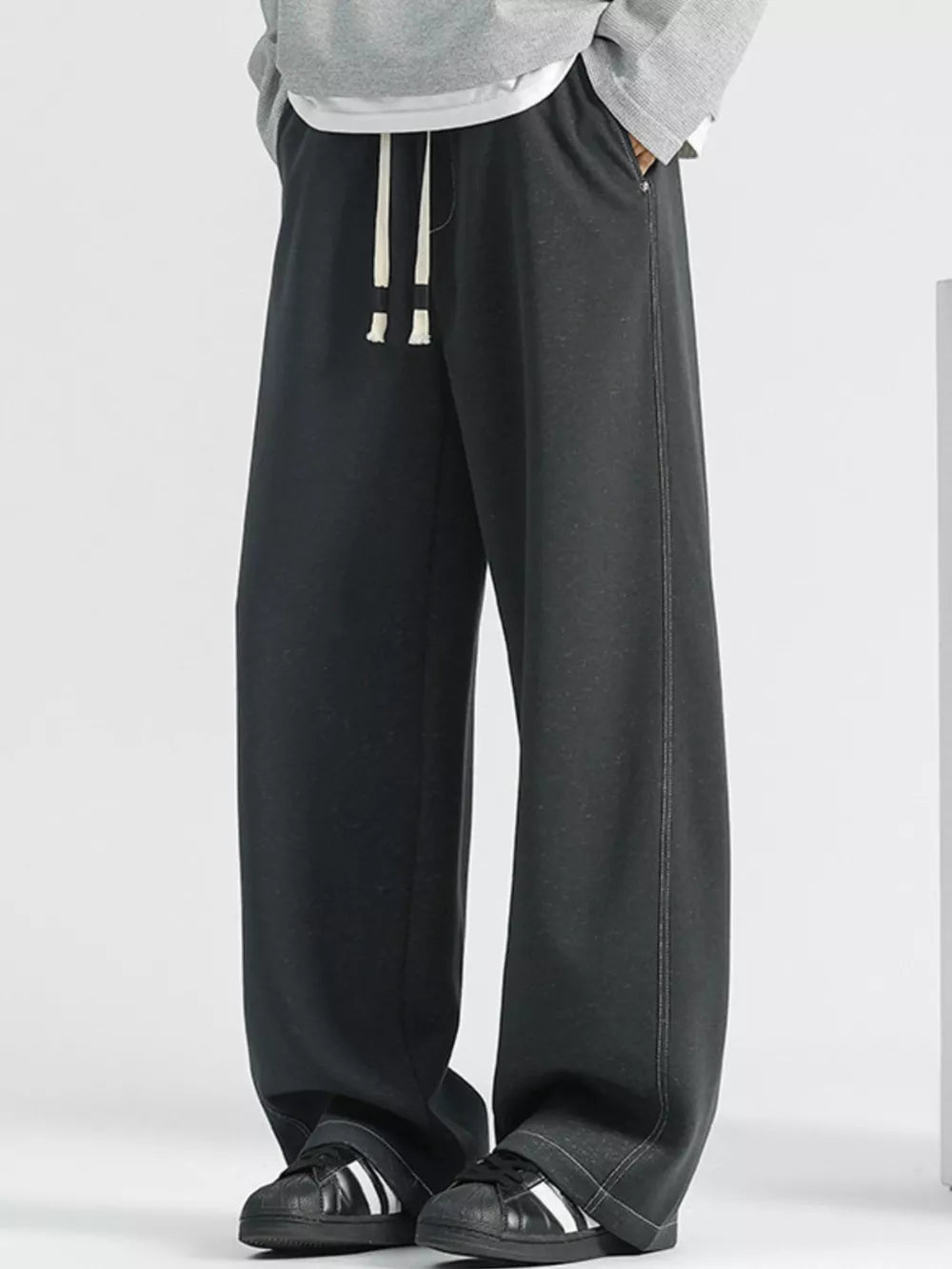 Men's dark gray loose fit drawstring jeans with white stitching detail.