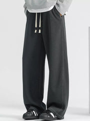 Men's dark gray loose fit drawstring jeans with white stitching detail.