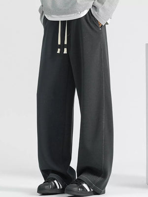 Men's dark gray loose fit drawstring jeans with white stitching detail.