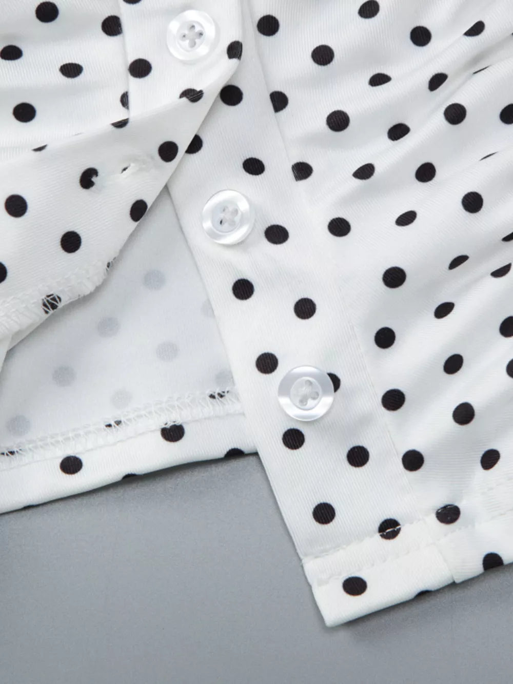 White polka dot t-shirt with button detail and ruched fabric.