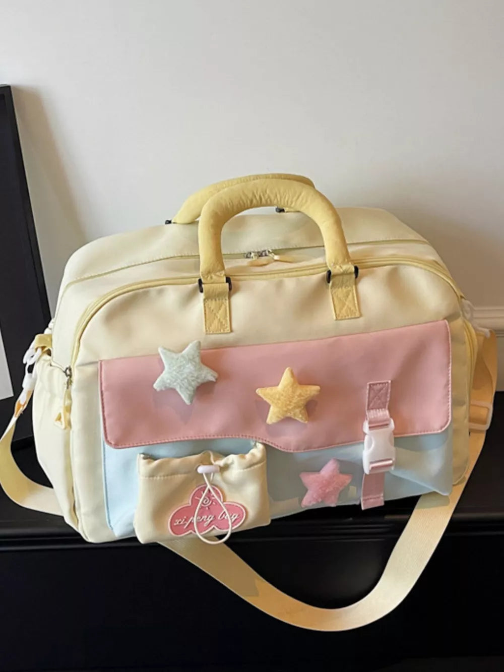 Chic color block travel bag with star embellishments and yellow handles.