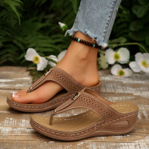 Khaki perforated leather thong wedge sandals with decorative buckle detail.