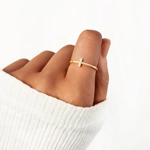 Rose gold pavé cross ring with sparkling stones on a delicate band.