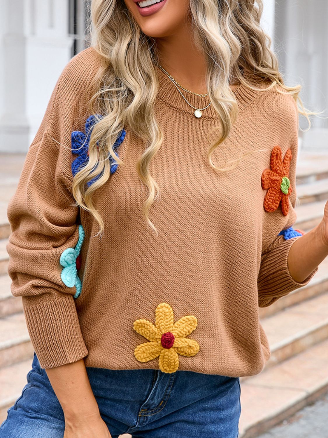 Camel knit sweater with embroidered floral appliqués and ribbed cuffs.