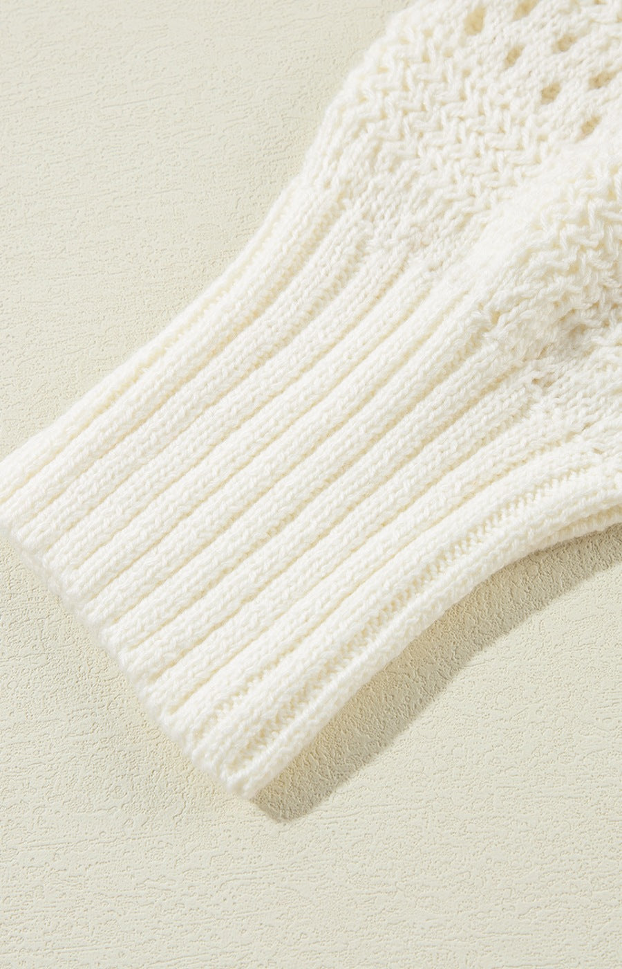 Cream openwork knit hoodie with ribbed sleeves and drawstring detail.