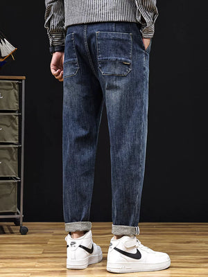 Men's relaxed fit denim jeans in medium wash with drawstring detail and cuffed hems.