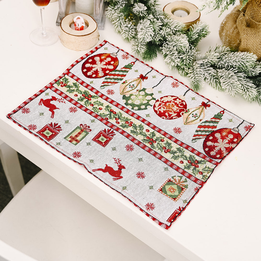 Embroidered Christmas placemat with ornaments, reindeer, and gifts in red and green on a light background.