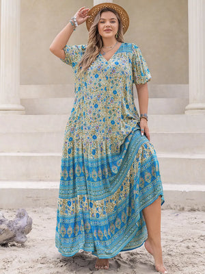 Bohemian floral maxi dress with tie waist, featuring a V-neck, short sleeves, and tiered skirt with blue border print.