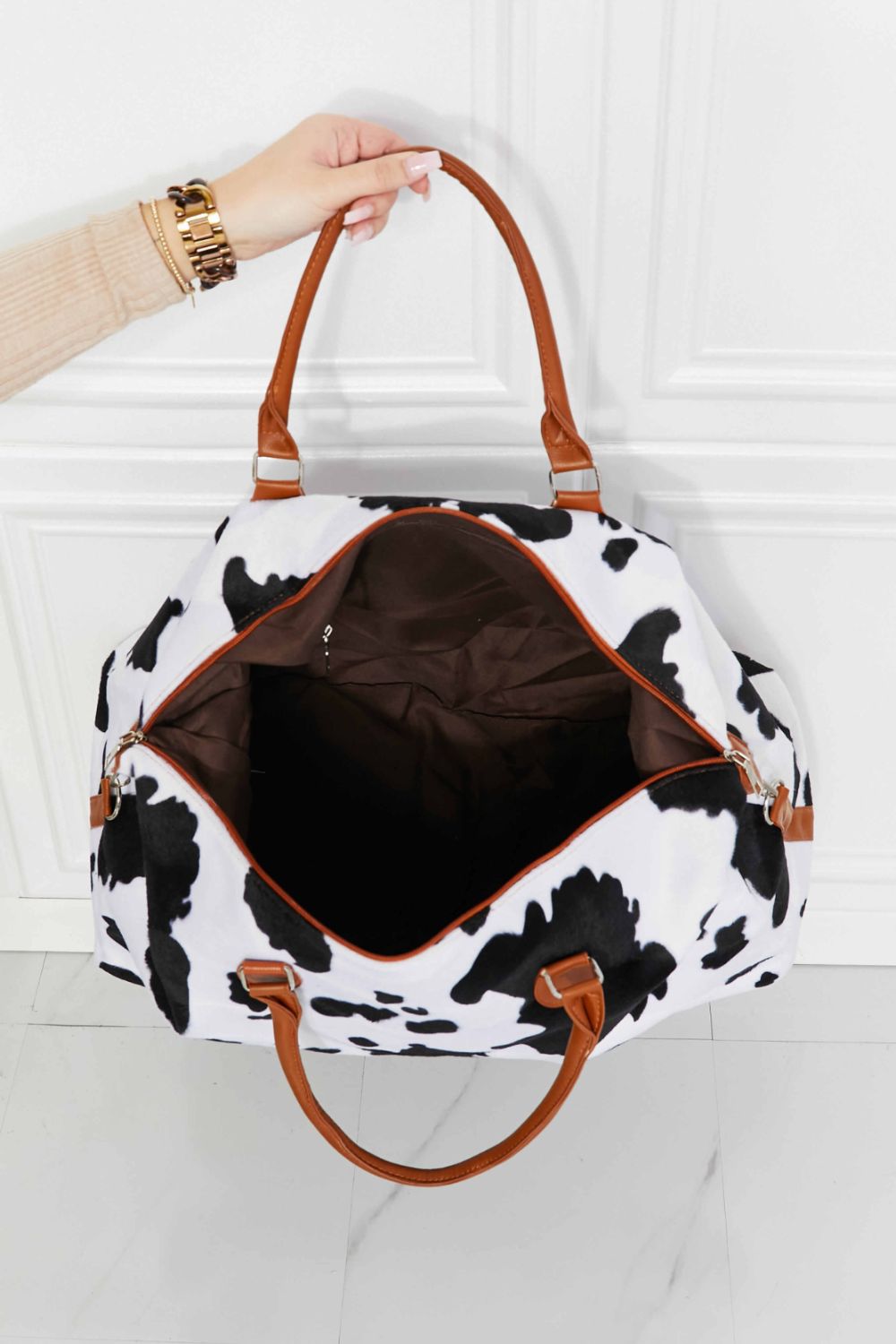 Cowhide print duffel bag with brown leather handles and trim