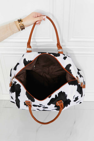 Cowhide print duffel bag with brown leather handles and trim