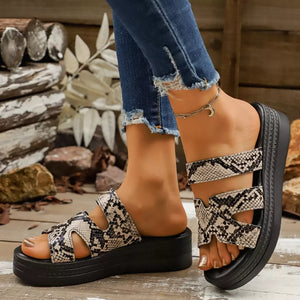 Snakeskin platform sandals with two straps and a thick sole, styled with distressed jeans.