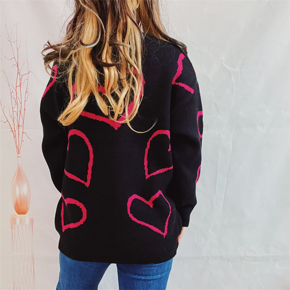 Black acrylic sweater with pink heart outline pattern, crew neck, long sleeves.