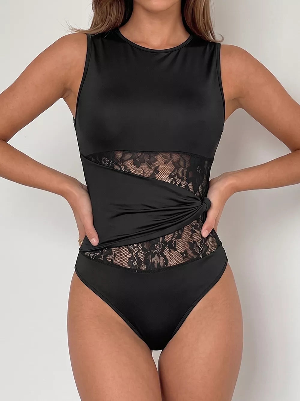 Black sleeveless bodysuit with sheer lace panels and a twisted detail.