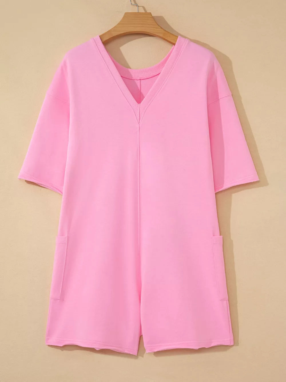 Pink cotton romper with V-neck, half sleeves, and patch pockets.