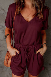 Burgundy V-neck romper with adjustable drawstring waist and cuffed short sleeves.