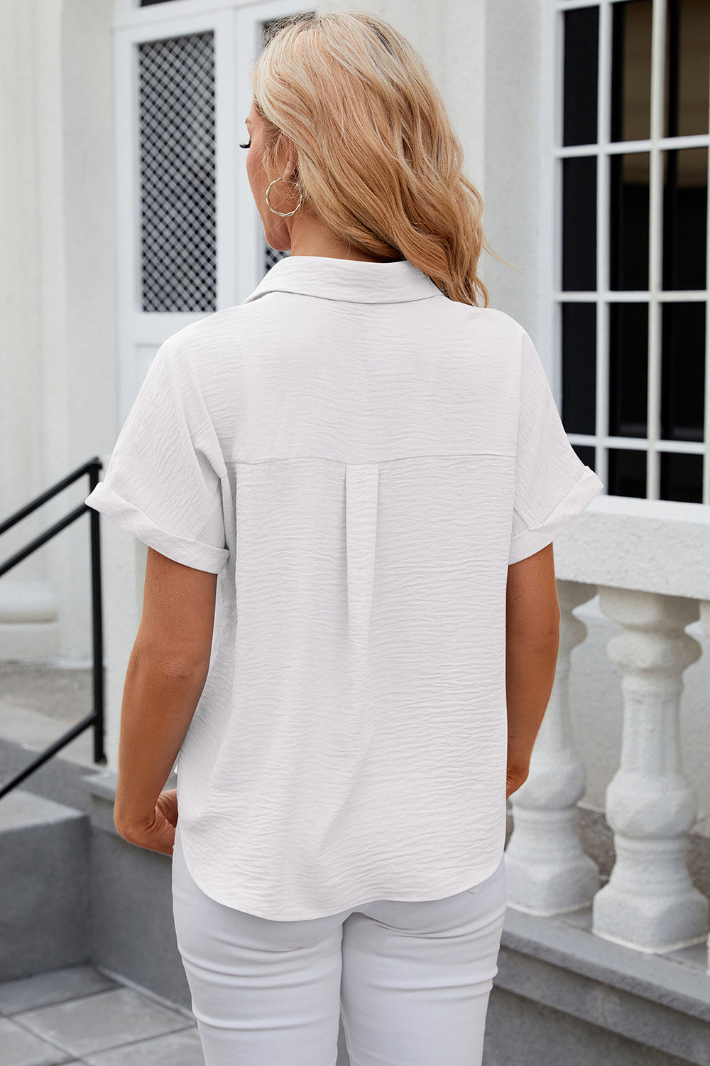 White textured short sleeve collared shirt with a button front and cuffed sleeves.
