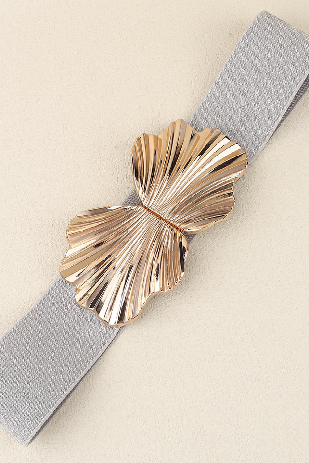 Elastic waist belt in grey with a sculpted gold butterfly buckle.