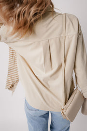 Beige corduroy shacket with houndstooth patchwork sleeve detail and back pleats.