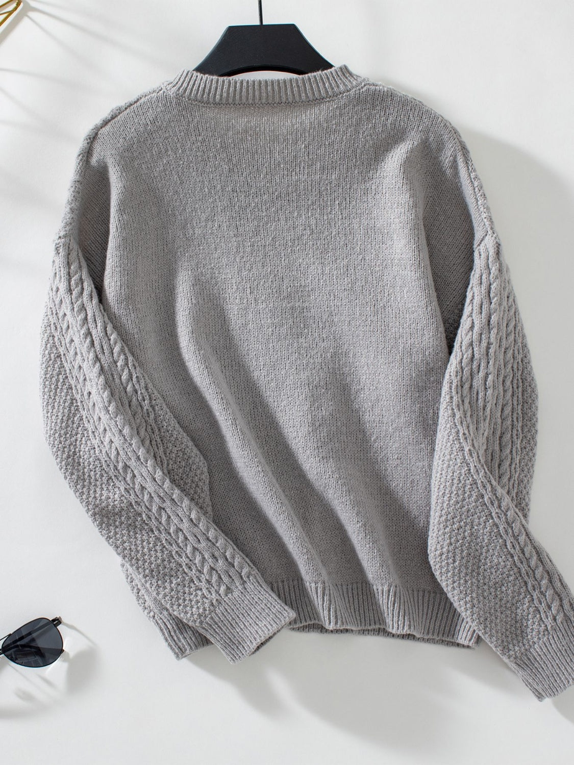Gray cable knit cardigan with textured sleeves and ribbed cuffs.