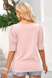 Blush pink blouse with puffed sleeves and button cuff detail.
