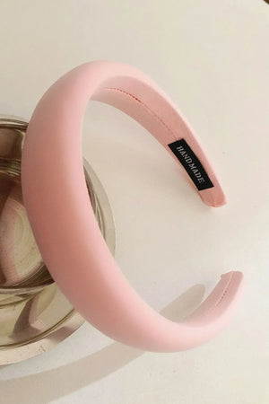 Padded pink headband with textured fabric and a handmade tag.