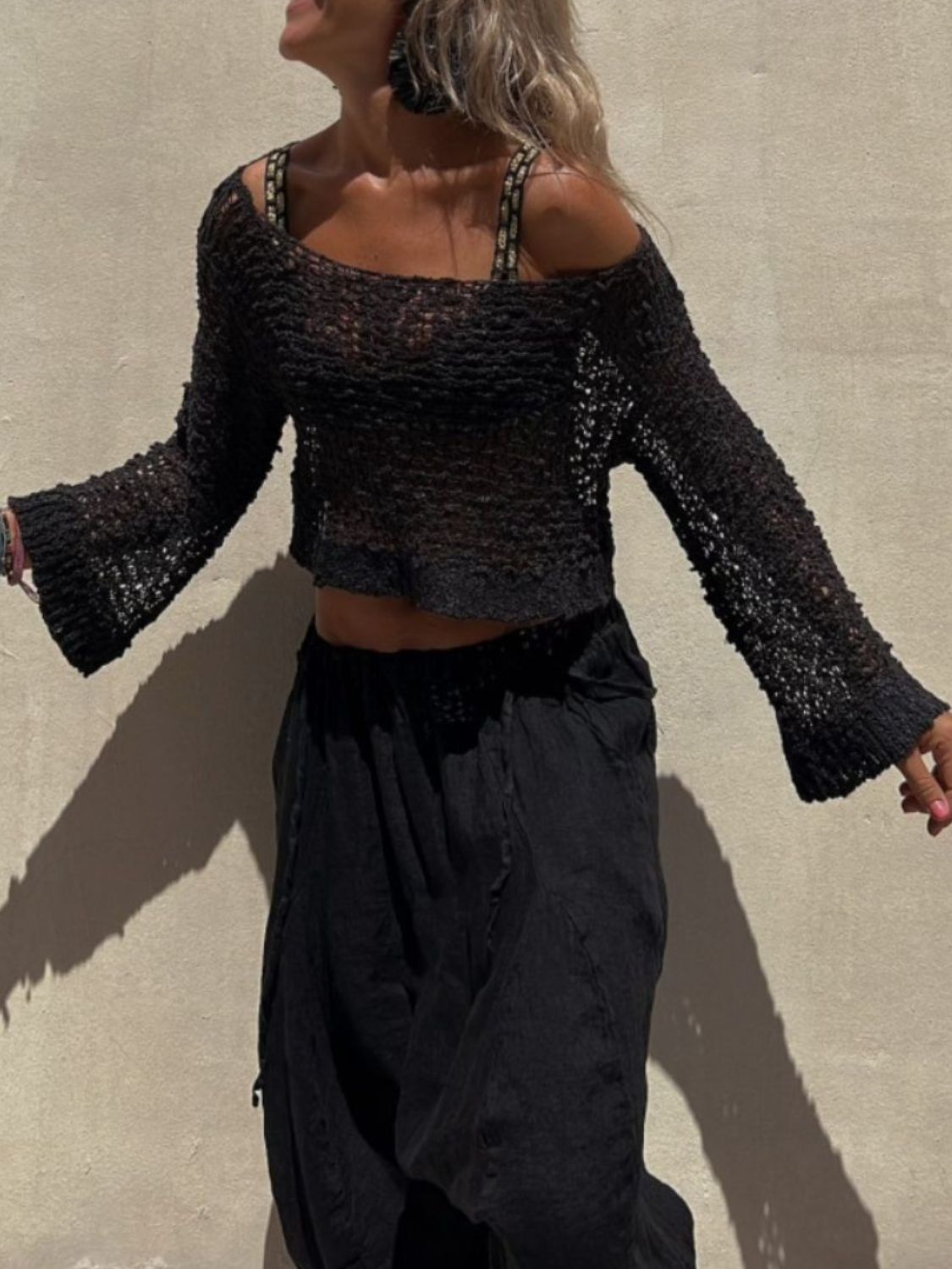 Black asymmetric crochet crop top with bell sleeves and a square neckline.