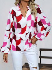 Geometric print blouse with voluminous sleeves and a ruffled V-neck in white with red and pink shapes.