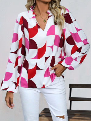 Geometric print blouse with voluminous sleeves and a ruffled V-neck in white with red and pink shapes.