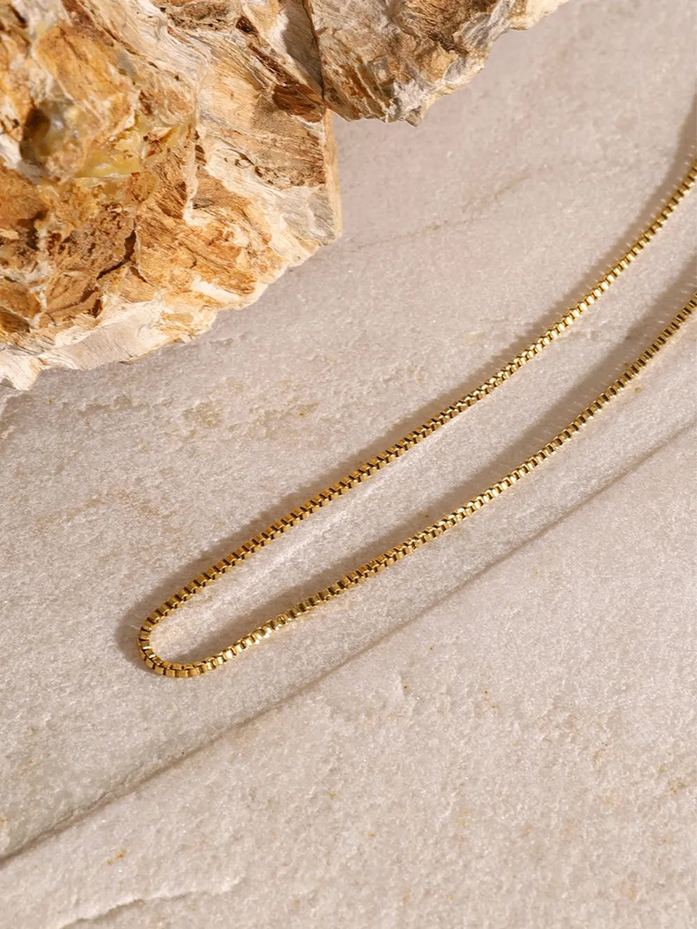 Gold layered necklace with a serpentine chain and cross pendant detail.