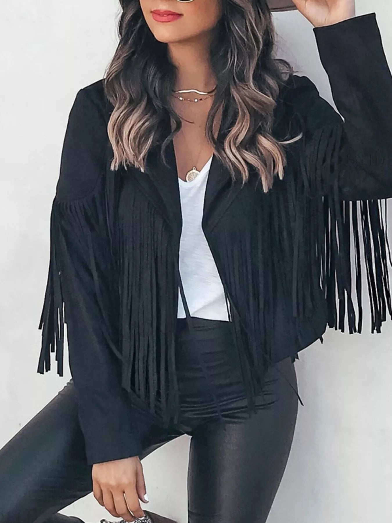 Black fringe open front cropped jacket with a white top and black pants.