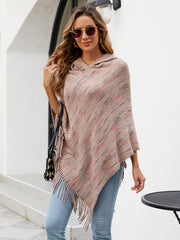 Hooded mélange cape with fringe detail in a neutral multi-color knit, styled casually.
