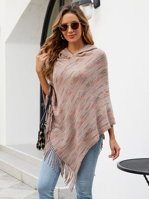 Hooded mélange cape with fringe detail in a neutral multi-color knit, styled casually.