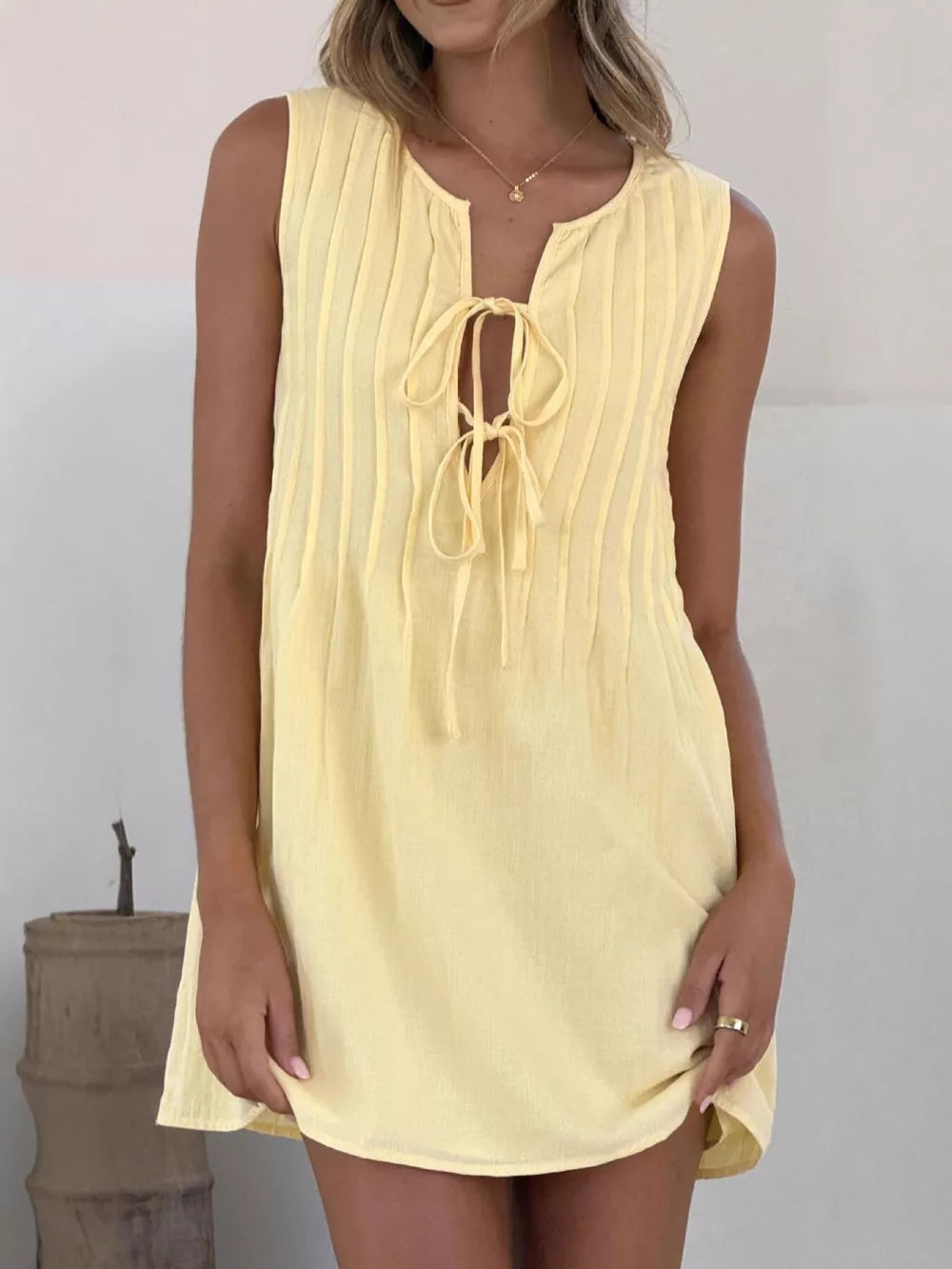 Yellow tie-front mini dress with vertical pintuck details and a keyhole neckline.