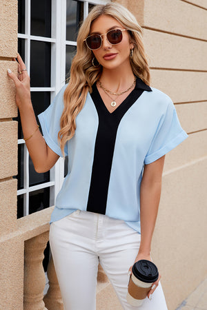Light blue blouson top with black V-neck contrast panel and cuffed short sleeves.