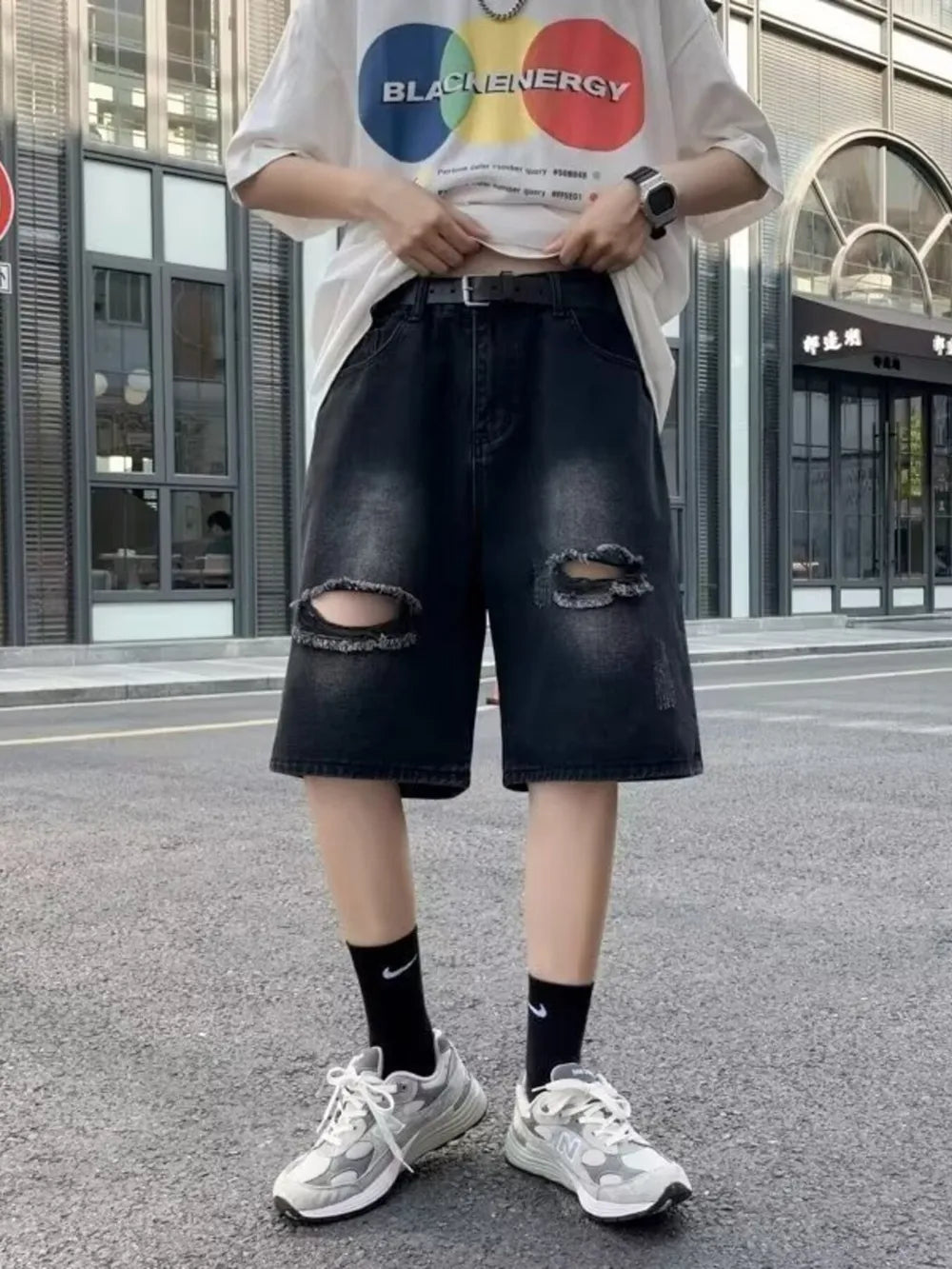 Black relaxed fit denim shorts with distressed knee rips and a frayed hem.
