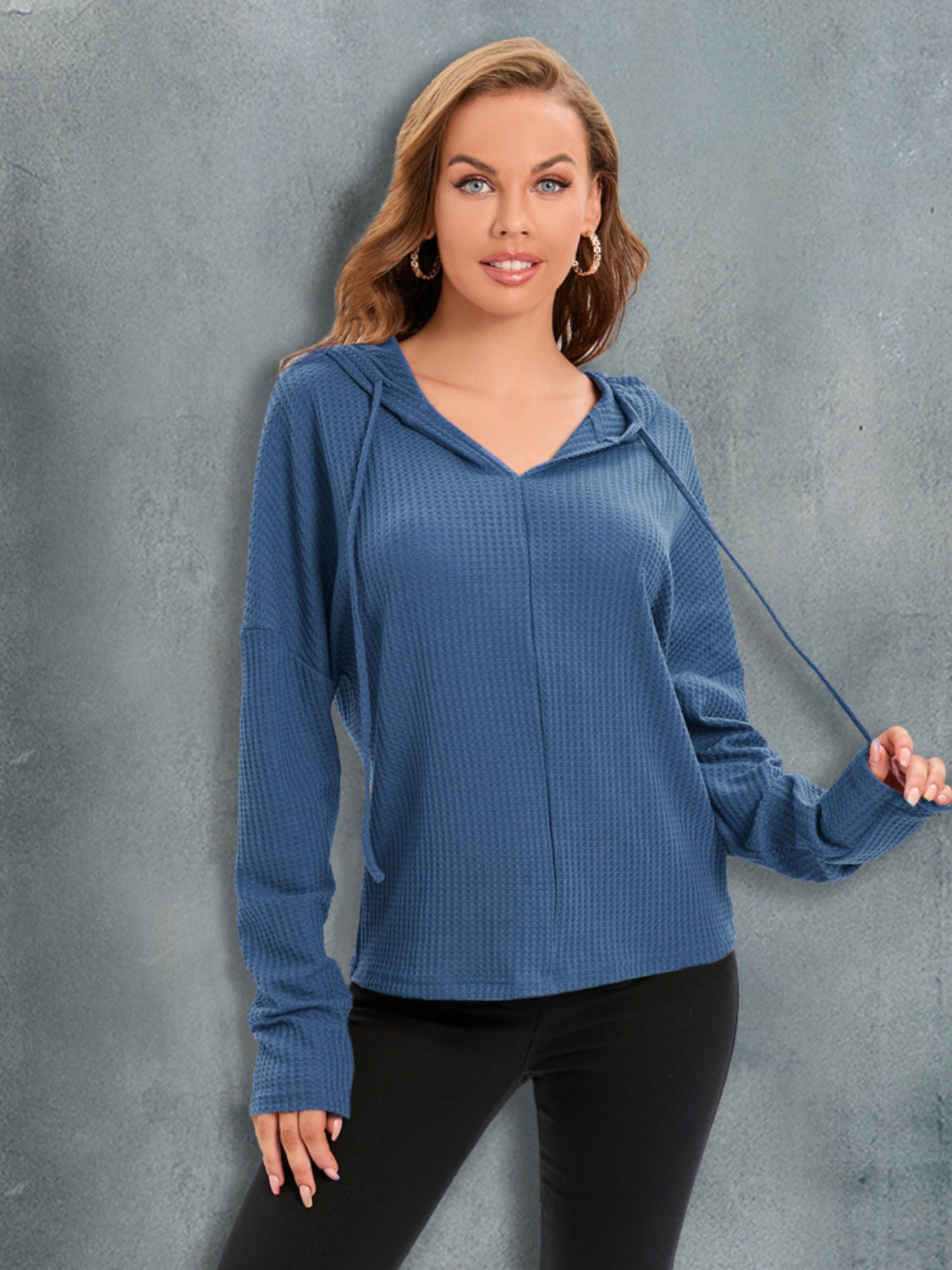 Dusty blue waffle knit hoodie with drawstring hood and relaxed fit.
