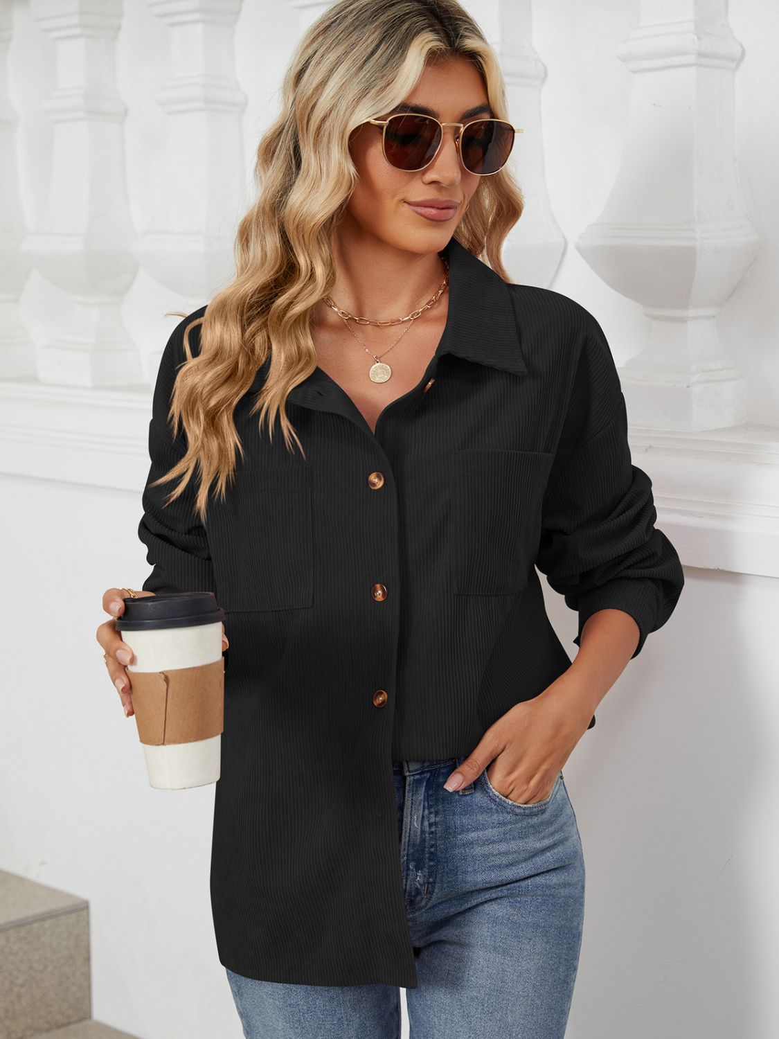Black corduroy overshirt with patch pockets and button front, worn by a model holding a coffee cup.