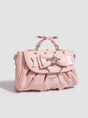 Pink ruched crossbody bag with bow, crown charm, and chain detail