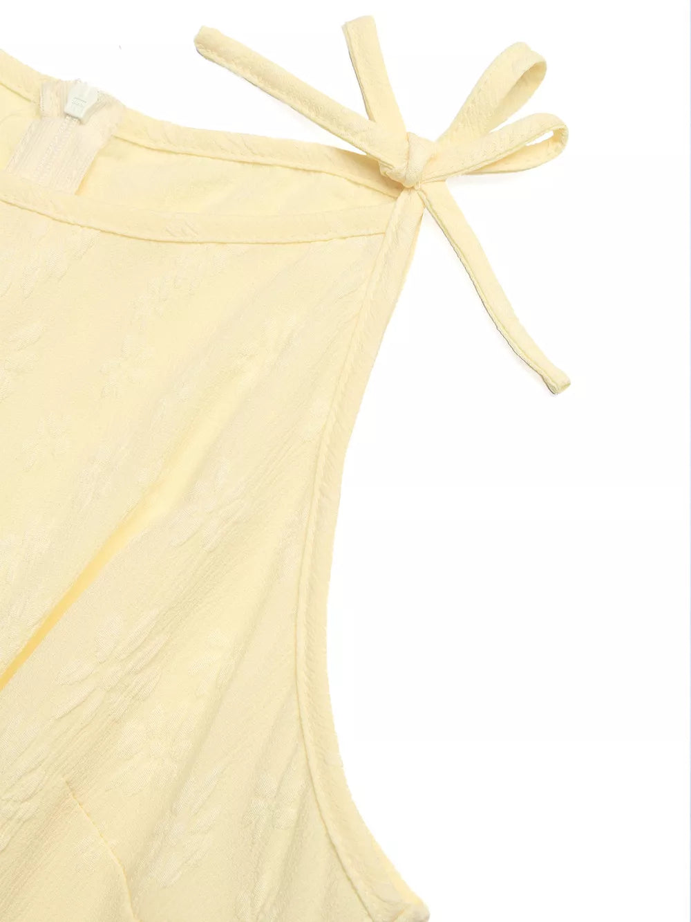 Yellow tie strap jumpsuit with textured fabric and a zipper detail.