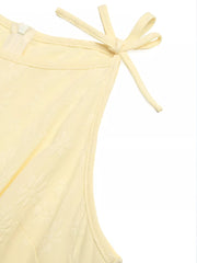Yellow tie strap jumpsuit with textured fabric and a zipper detail.