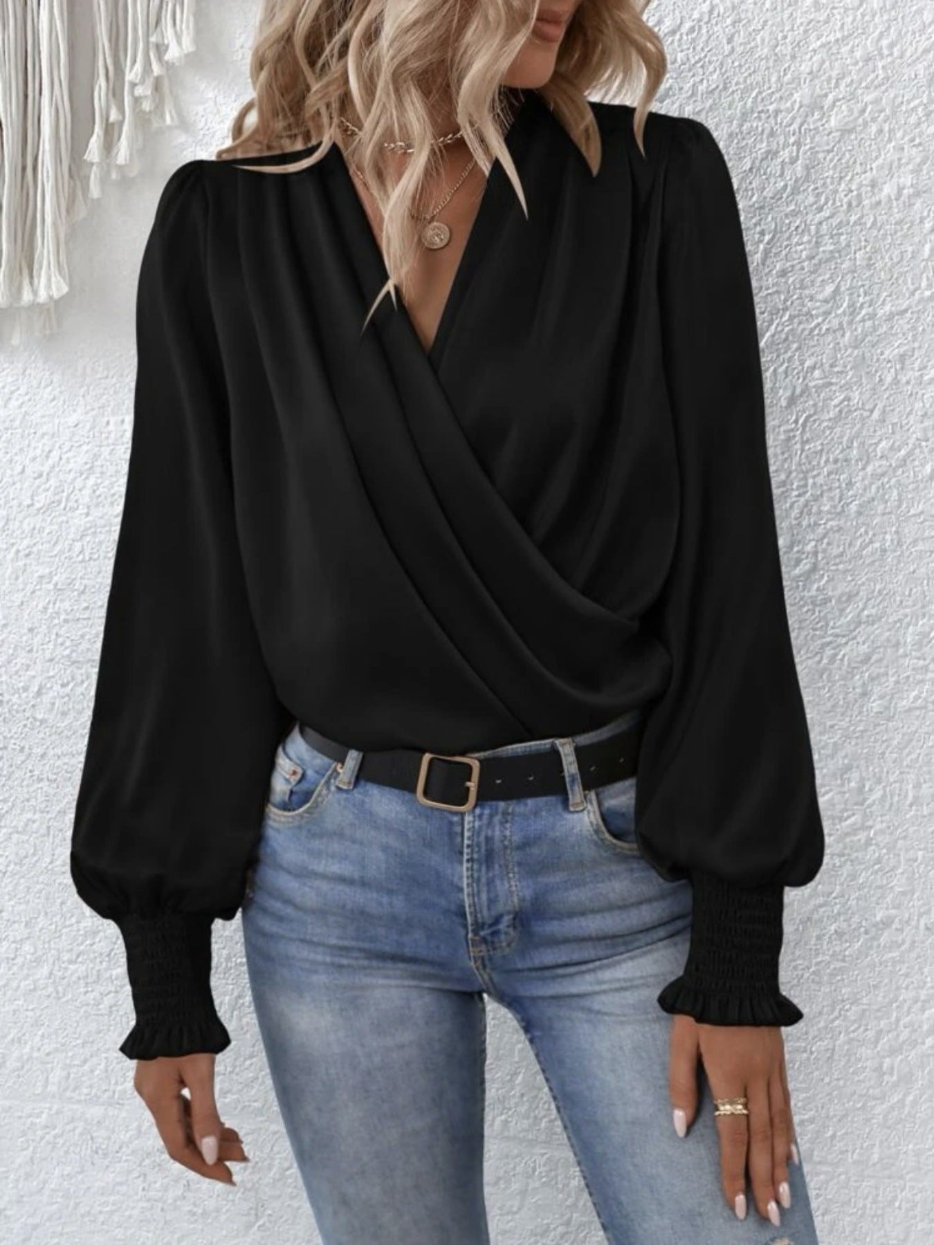 Black ruched surplice blouse with V-neck and bishop sleeves with smocked cuffs.