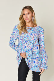 Painterly print blouse in sky blue with gathered sleeves and a round neckline.