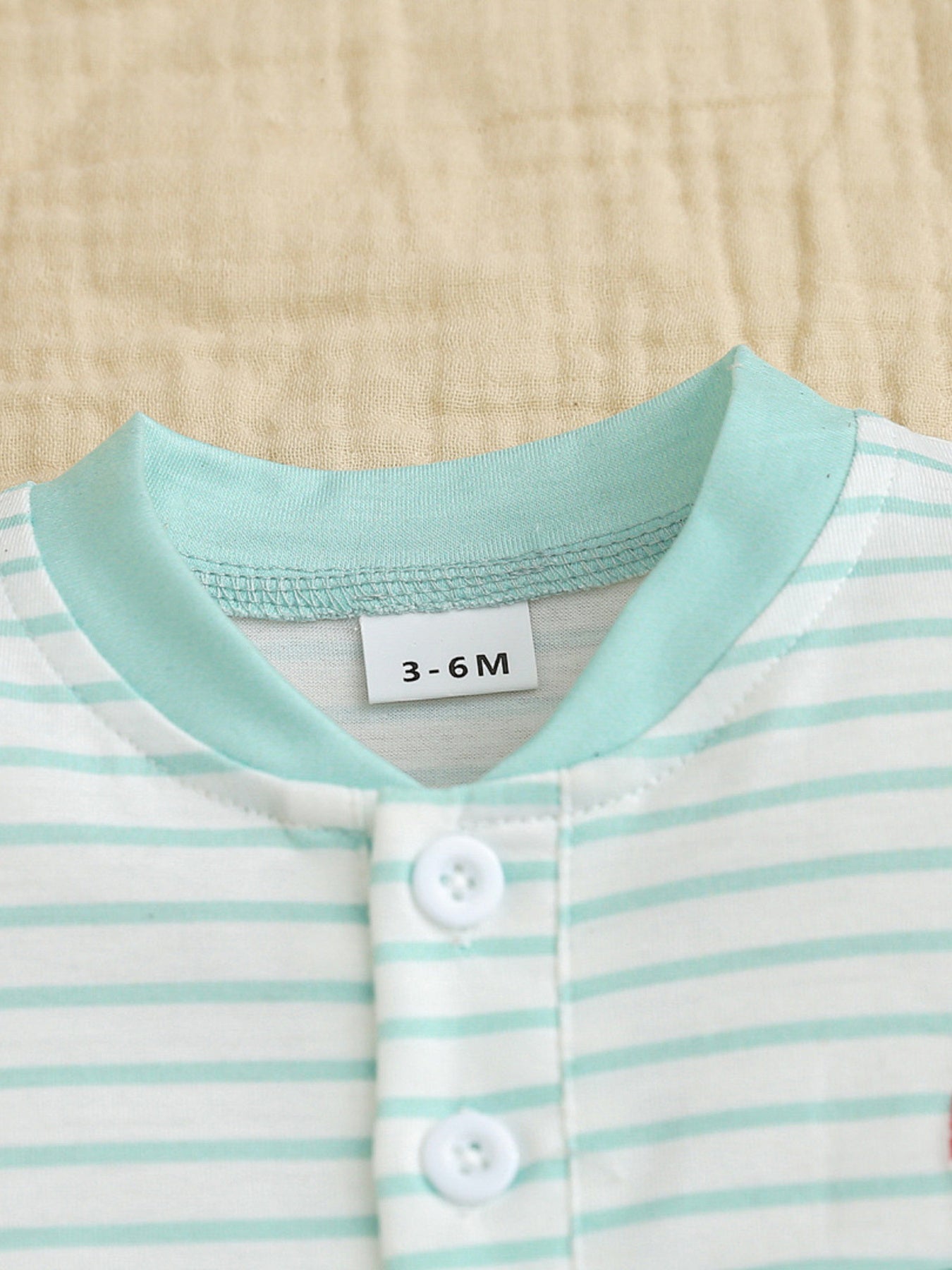 Baby bodysuit with mint green and white stripes, round neck, and button closure.
