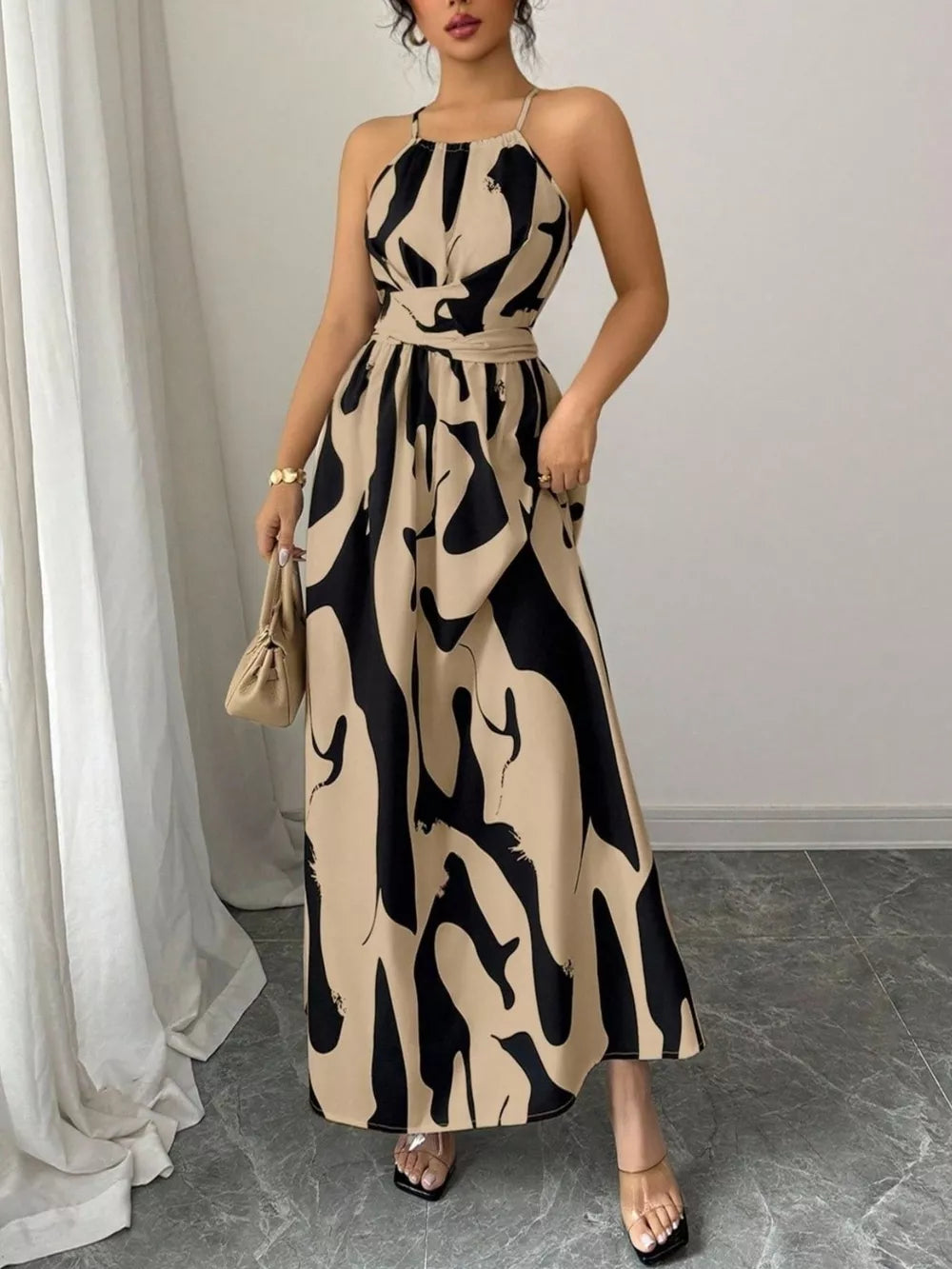 Chic halter neck maxi dress with abstract print in beige and black, belted waist, ankle length.