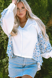 White waffle knit blouse with blue floral print sleeves and V-neck.