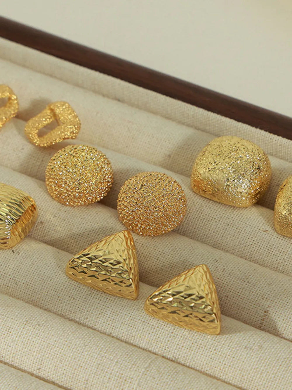 Gold textured cube earrings in various geometric shapes and finishes.