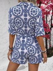 Blue and white printed tie-waist romper with short sleeves and collar, shown from the back.